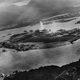 In a photo taken by a Japanese pilot, a plume of water rises from a torpedo that struck USS West Virginia (BB 48) moored on Battleship Row on the far side of Ford Island. A Japanese aircraft can be seen banking over the island, while another flies over the Navy Yard at the top right of the photo. Though struck by six torpedoes and two bombs, West Virginia was salvaged, refitted, and took part in the Battle of Leyte Gulf in 1944 and was present for the signing of the Japanese surrender in Tokyo Bay on September 2, 1945. (US Navy)